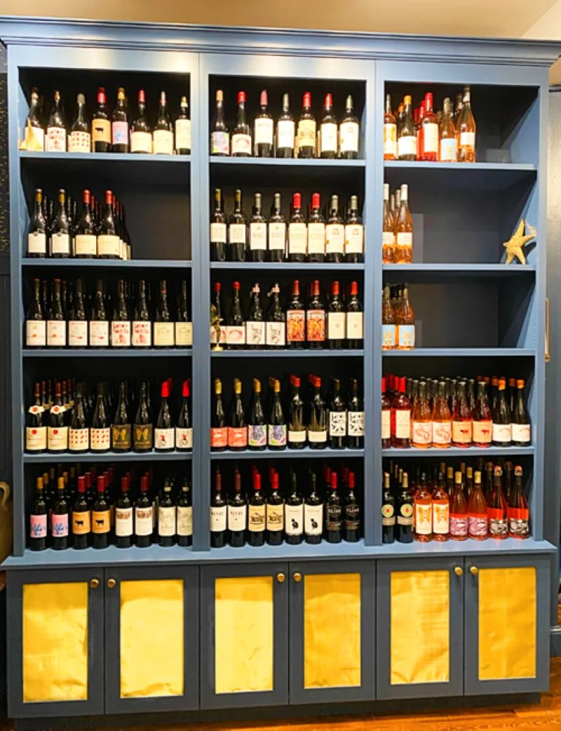 Custom wine display cabinets in Farrow & Ball blue paint.  Upper shelves are open and lower cabinet doors feature a brass wire mesh panel.